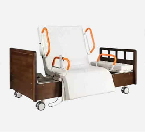 An electric rotating hospital bed for home use with orange handrails, a white mattress, and a brown wooden headboard and footboard. The bed is on lockable wheels and has control panels.